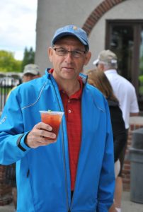 man in blue jacket holds up bloody mary drink