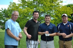 group of four men posing with hands on golf clubs