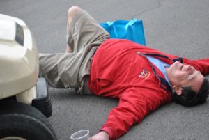 man in red jacket lying on his back in protest of golf cart moving