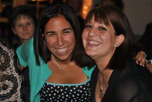 woman in teal button up smiles with woman in black