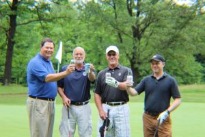 group of four toasting beers on golfing green