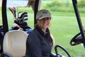 woman smiling in golf cart with aim services hat