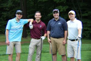 four golfers resting arms on one another smiling for camera