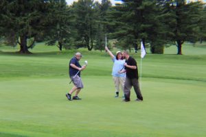 group of three celebrating with fist pumps on the green