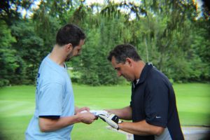 man in blue hands out large playing card to golfer