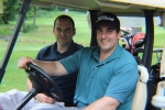 two guys in golf cart smiling