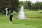 woman teeing off over a pond