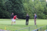 golfers watch a man hit the green