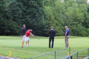 man goes for long putt while three watch