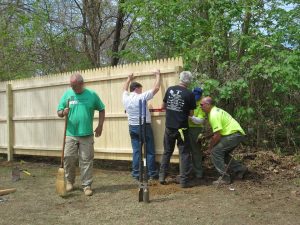 group of five men putting up a new fence