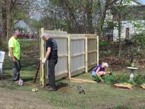 view of fence being built with woman planting flowers