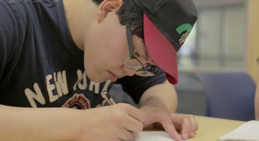 man focusing hard while writing on paper