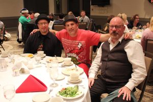 three men at dinner table with christmas themed clothing