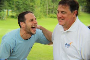 man in blue laughing hysterically with man in white polo