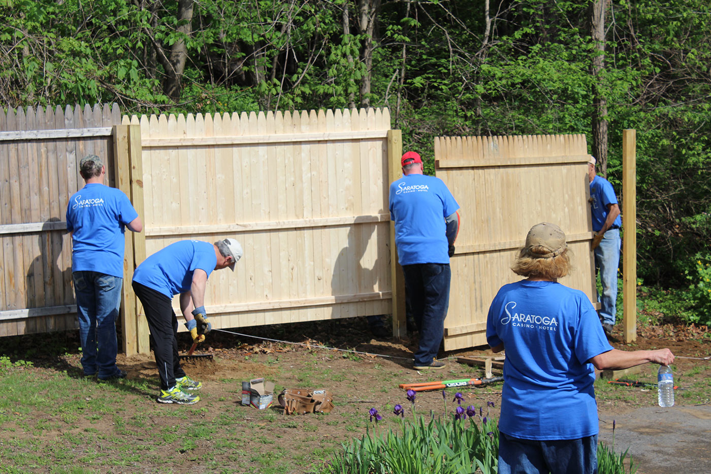 Men building a wooden fence and doing spring clean-up at the backyard