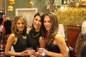 three woman smiling and holding wine glasses at vin le soir event