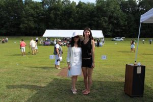woman in large white hat poses with young woman