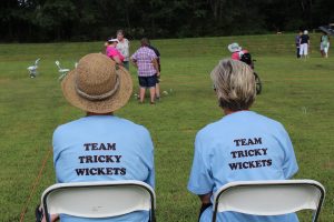 two women sitting showing off custom Team Tricky Wickets shirts