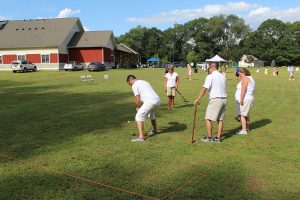 team of four in white watching man go between the legs croquet shot