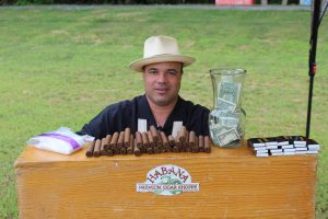 man with hat sitting at his habana cigar stand
