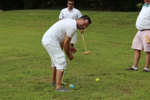 man bending over laughing and analyzing next croquet play