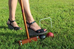 close up on woman's heel doing trick shot with croquet balls