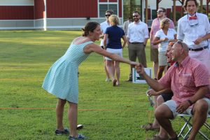 woman seemingly gloating to two men over croquet win