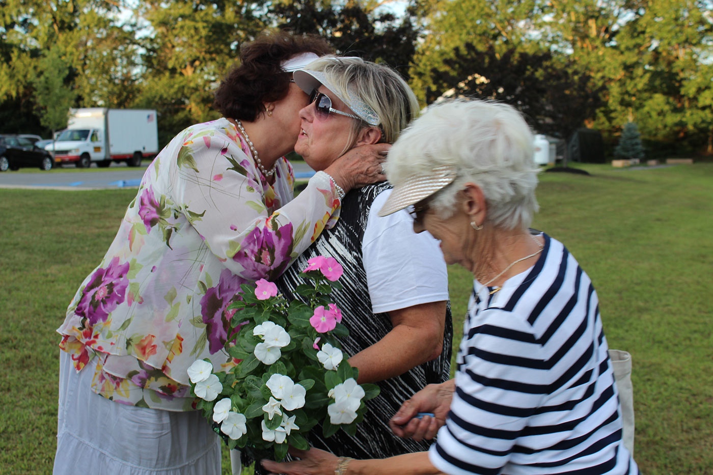 Old women kiss and hug one another in white clothes outdoor
