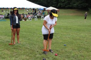 girls with large yellow visors playing croquet