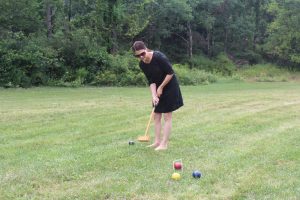 woman in black dress and large sunglasses admiring croquet shot