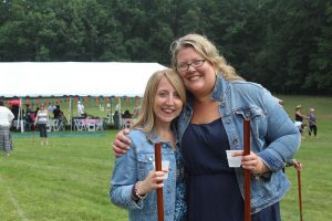 two women in jean jackets holding croquet mallets and cups of water
