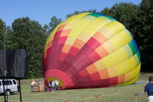 large rainbow hot air balloon being prepared on ground