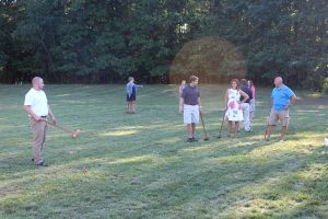 view of multiple people on field, talking and playing croquet