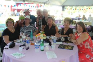 nine women posing goofy sitting around table