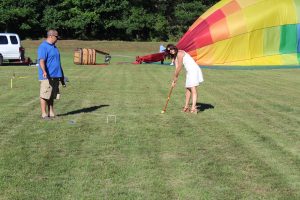 woman lining up croquet shot with hot air balloon deflated in background