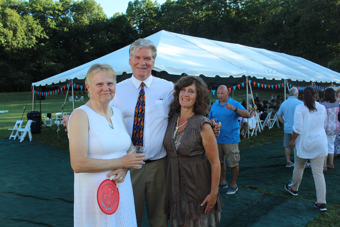 three people standing outside the tent smiling