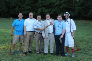 group of six men smiling for a photo on the croquet field