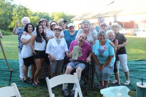 large group of women smiling with man in wheelchair at the center