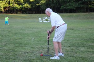 older gentleman lines croquet mallet up with red ball