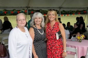 three women smiling for photo under main tent