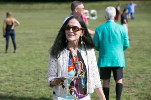 woman with black hair and sunglasses walking across croquet grass