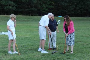 group of croquet players with one man measuring how close ball is to steak