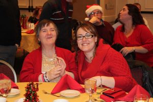 two women in red smiling and laughing at dinner table