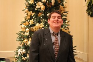 young man smiling with elegant christmas tree in background