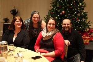 group of four smiling at table near christmas tree