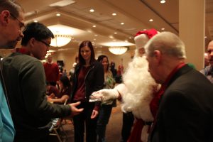 santa handing out what looks to be bracelets to party goers