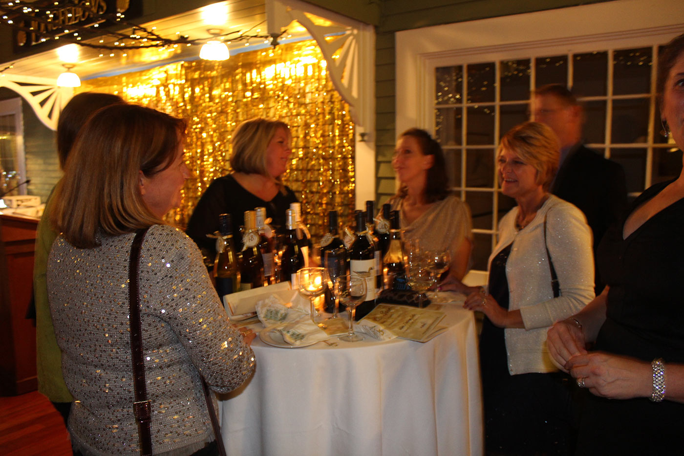 guests gathered around a table stocked with wine