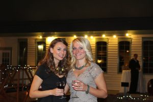 two women smiling and toasting wine glasses