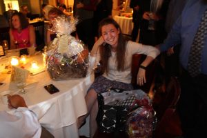 woman sits proudly with two winning raffle gift baskets