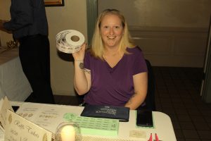 woman in charge of raffle tickets holds up large roll of tickets